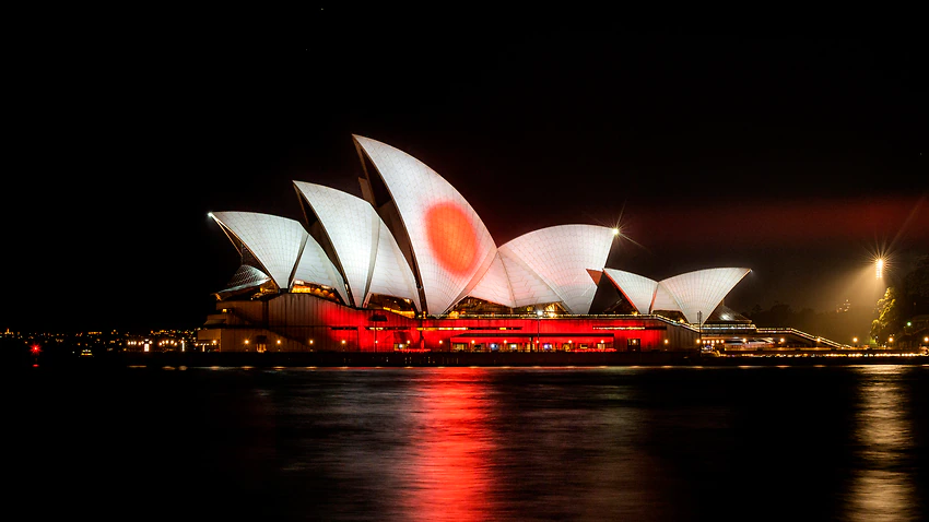 赤と白に投影されたシドニーのオペラハウス